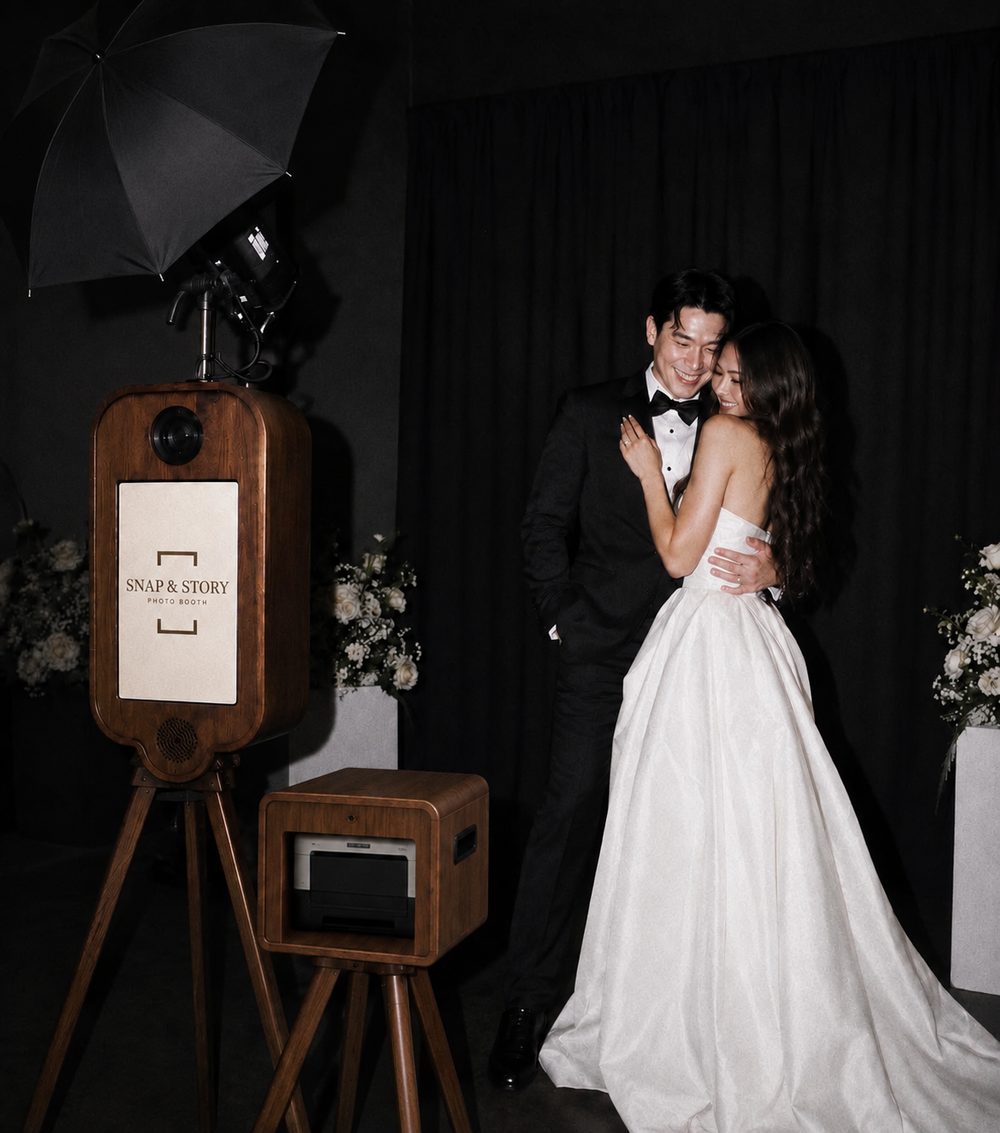 A couple embracing beside the Snap & Story wooden booth